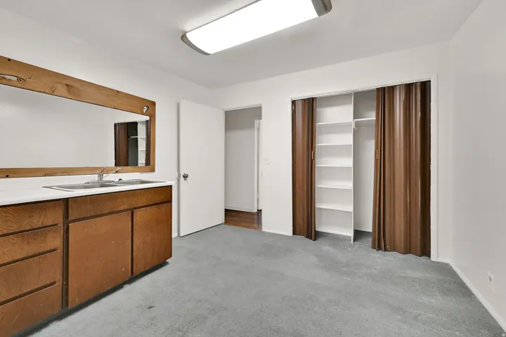 Interior space featuring a built-in vanity with a rectangular sink, wood-finish cabinetry, and a large framed mirror