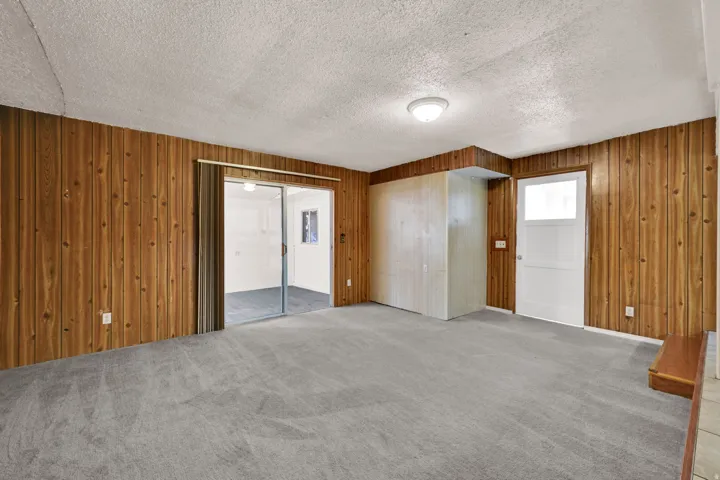 Spacious room featuring wood paneling, gray carpeting, and a white ceiling