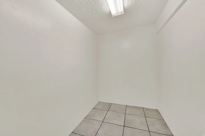 White-painted interior space featuring tile flooring and a ceiling-mounted fluorescent light fixture