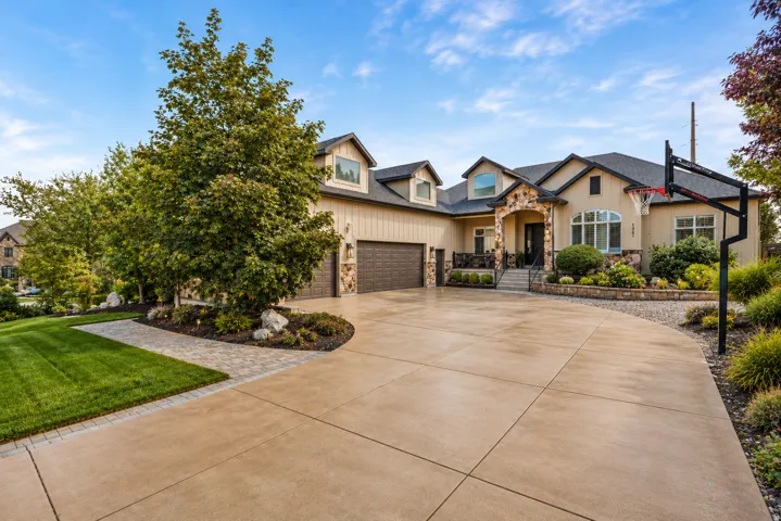 Spacious concrete driveway featuring a decorative paver stone walkway
