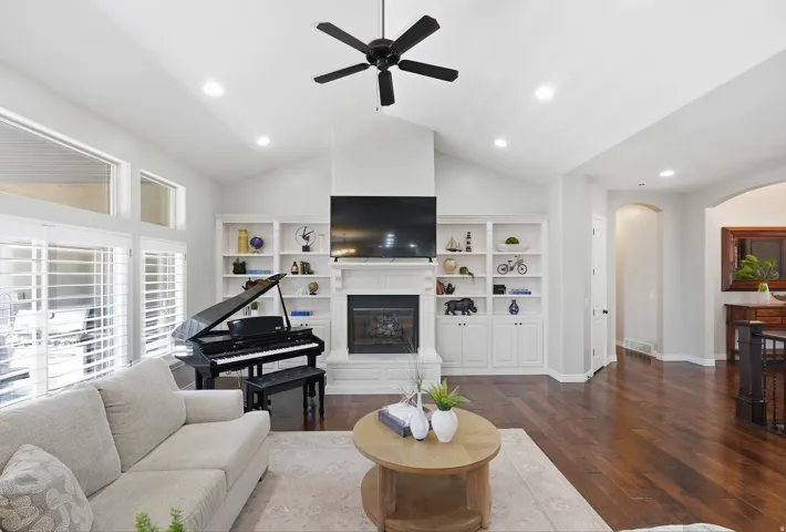 Spacious living area featuring vaulted ceilings, recessed lighting, and rich wood-finish flooring