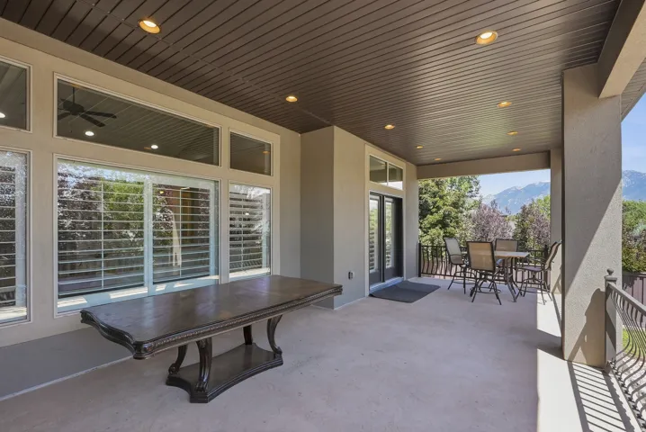 Expansive covered patio featuring recessed lighting, a ceiling fan, multiple large windows, and an ornate wrought iron railing