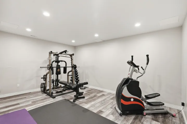 Spacious interior room with wood-finish flooring, recessed lighting, and light-toned wall paint