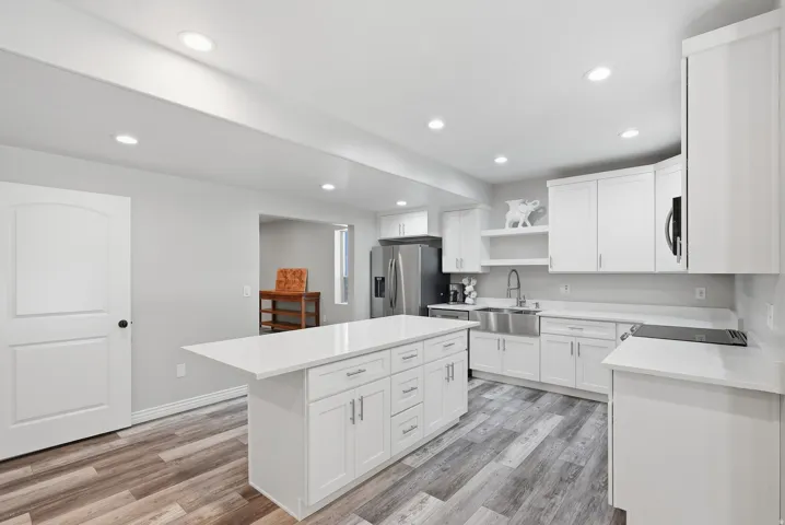 Contemporary kitchen featuring an expansive center island with white cabinetry and a light-toned countertop