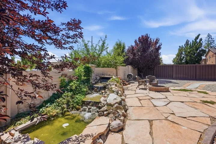 Expansive outdoor space featuring a multi-tiered water feature with a pond, flagstone patio, and a stone fire pit
