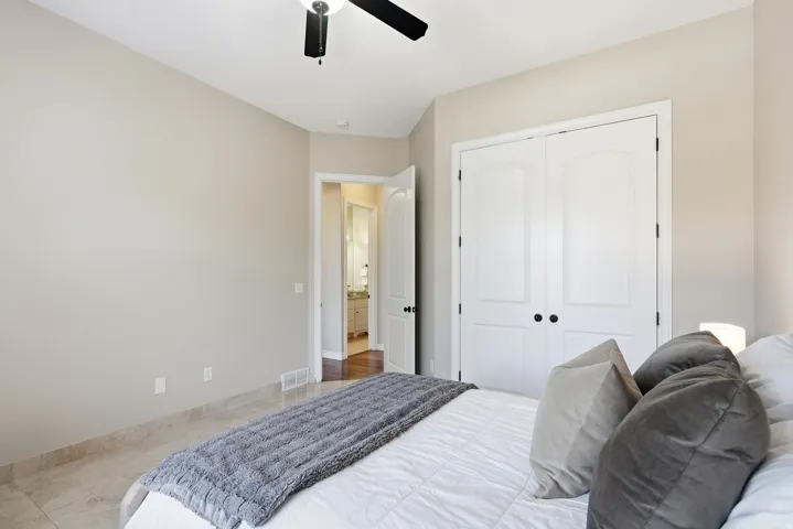 Bedroom featuring light-toned wall paint, tiled flooring, and a ceiling fan