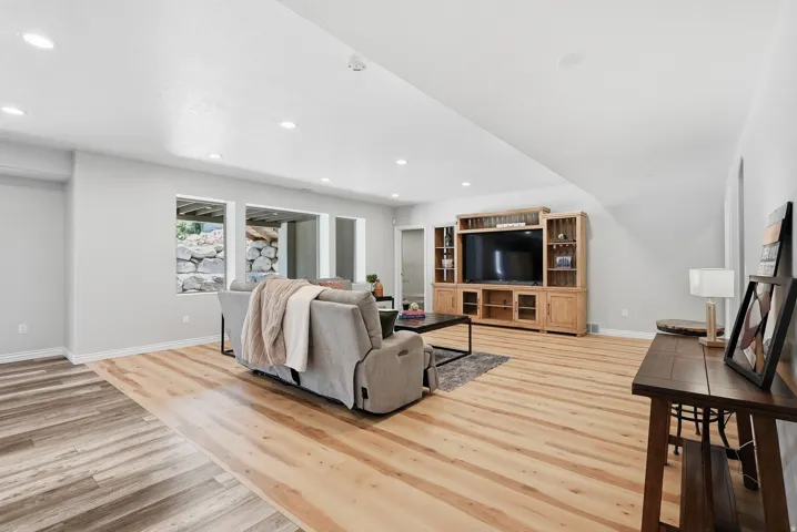 Spacious entertainment room featuring recessed lighting, a large built-in media console, wood-finish flooring, and multiple window openings