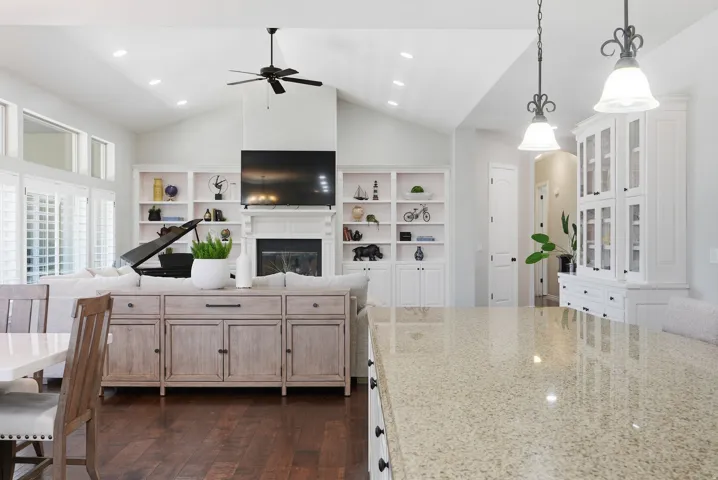 Spacious great room featuring vaulted ceilings, wood-finish flooring, and built-in shelving surrounding a fireplace