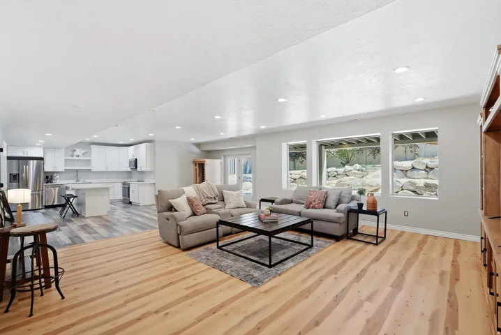 Open-concept living space featuring light wood-finish flooring, recessed lighting, and multiple windows