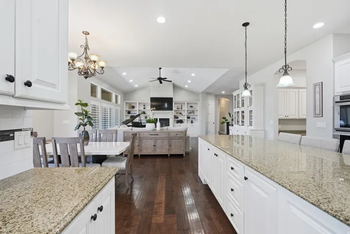 Kitchen featuring white cabinetry, light-toned stone countertops, and pendant lighting over a large island