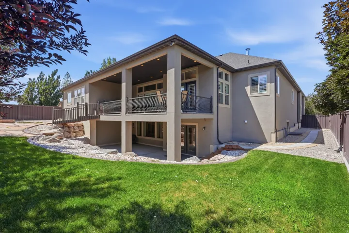 Stucco exterior featuring a dual-level covered patio and deck with wrought iron railings