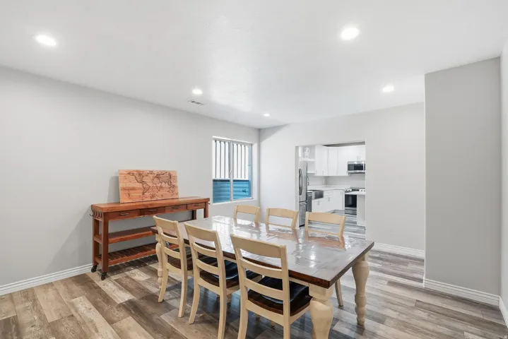 Spacious dining area featuring wood-finish flooring, recessed lighting, and a window with horizontal blinds