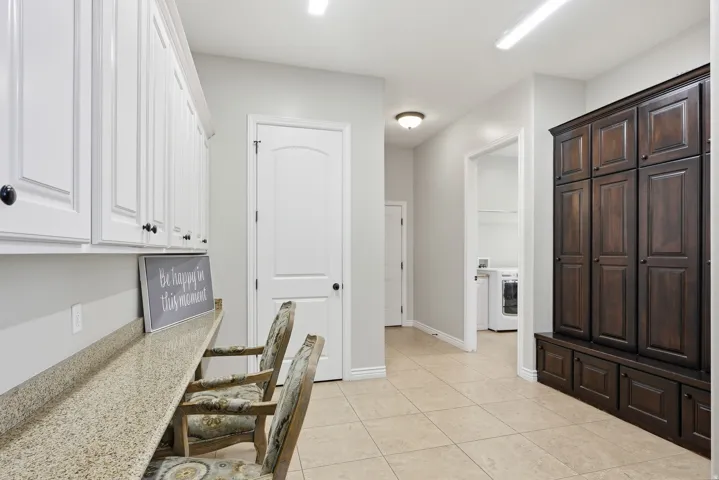 Hallway featuring extensive white cabinetry with black hardware, a long speckled countertop, and large dark wood cabinetry with lower storage