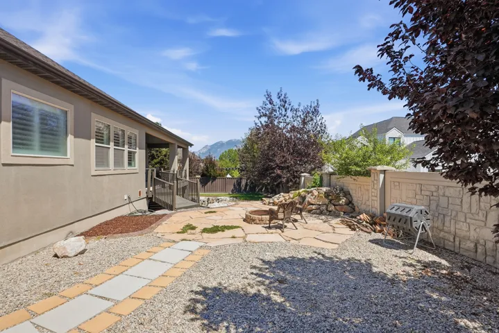 Exterior patio featuring flagstone paving, a built-in fire pit, and a stone retaining wall