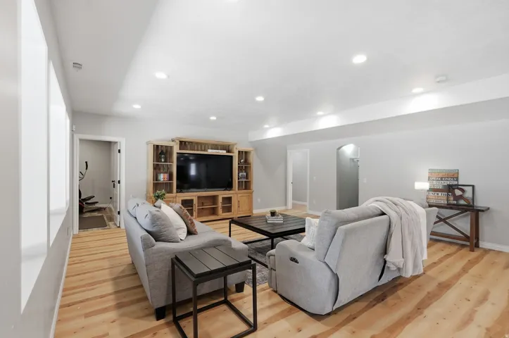 Spacious entertainment area featuring wood-finish flooring and recessed lighting
