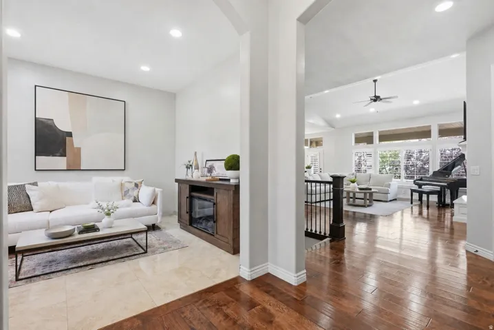 Open concept living areas featuring high ceilings, wood-finish flooring, recessed lighting, expansive windows, and a built-in beverage refrigerator