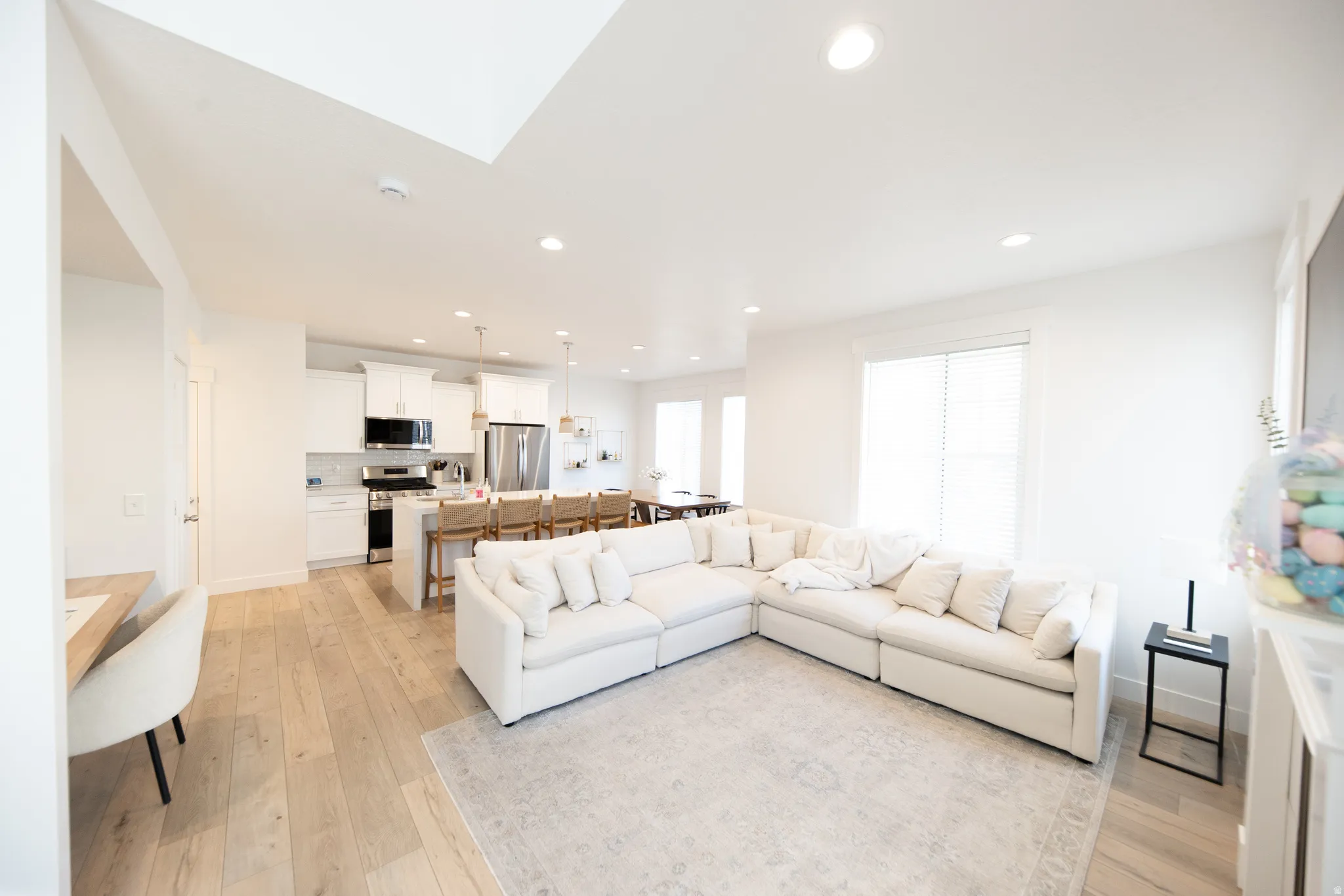 Open-concept living space featuring wood-finish flooring, recessed lighting, and white walls