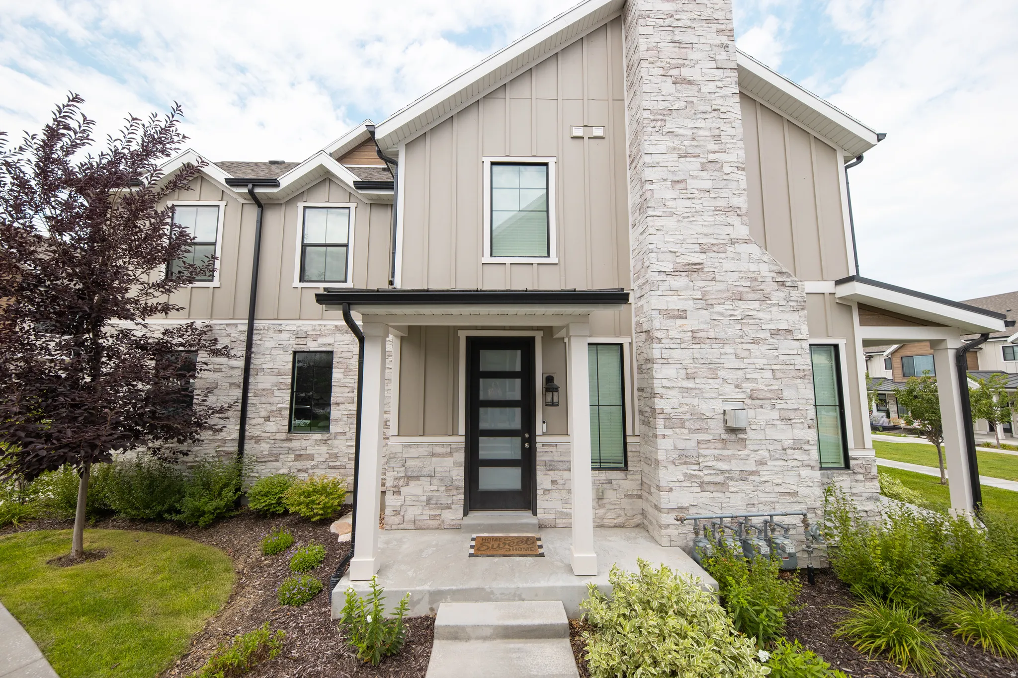Contemporary home exterior featuring board and batten siding and light-colored stacked stone accents