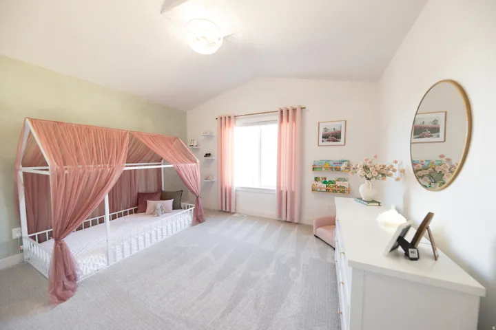 Spacious room featuring vaulted ceilings, a large window with privacy coverings, soft carpet flooring, and a contemporary ceiling light fixture