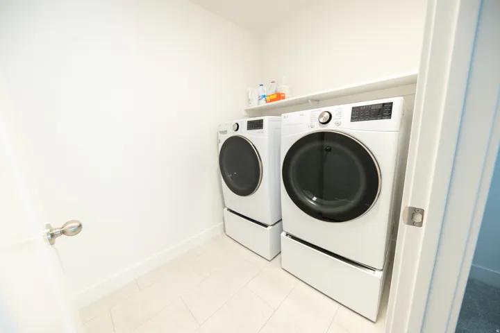 Laundry area featuring light-toned tile flooring and a built-in storage shelf