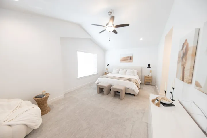 Spacious room featuring vaulted ceilings, a ceiling fan, recessed lighting, a wide window, and light-toned carpeting