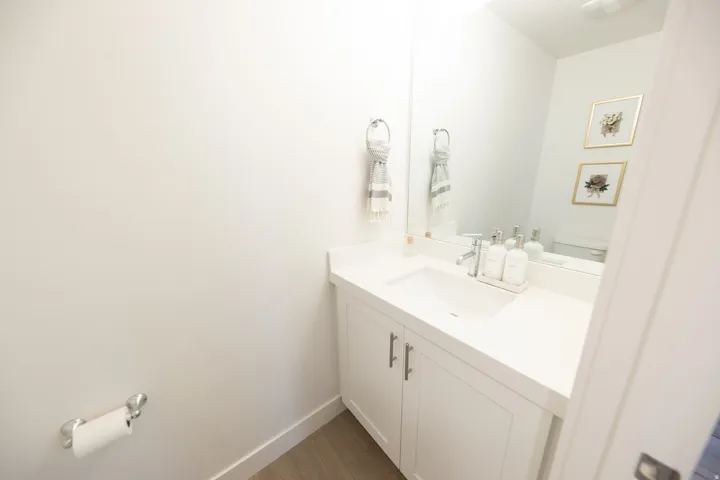 Bathroom featuring a white vanity with paneling, integrated sink, and a large mirror