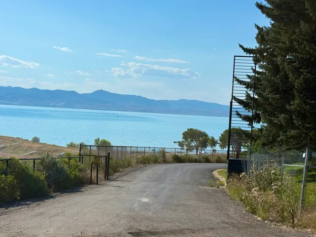 Paved driveway leading to a water feature with distant mountains