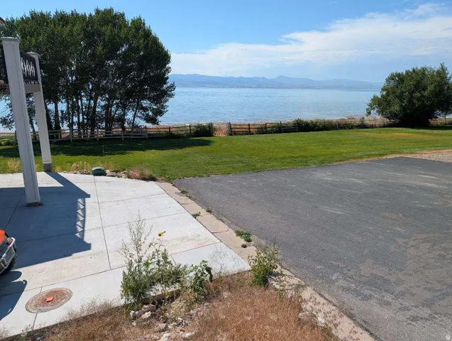 Expansive waterfront property featuring a large green lawn, mature trees, and a paved driveway
