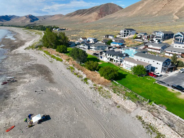 Lakeside community featuring a mix of multi-story and single-story residences, expansive green lawns, and a natural rocky shoreline
