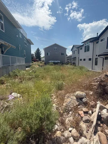 Expansive undeveloped lot featuring natural vegetation and surrounding contemporary architecture