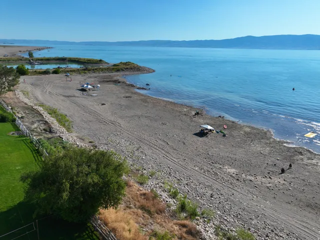 Expansive waterfront property featuring a gravel beach shoreline and clear blue waters