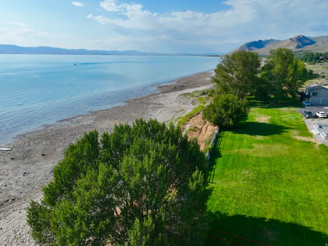 Expansive waterfront property featuring a large green lawn and mature trees