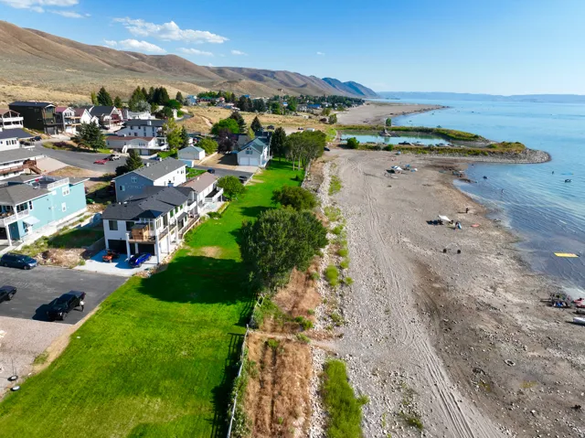 Waterfront property featuring a landscaped lawn and multiple homes situated along a shoreline