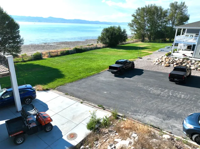 Expansive waterfront property featuring a manicured lawn, gravel beach, and mountainous backdrop