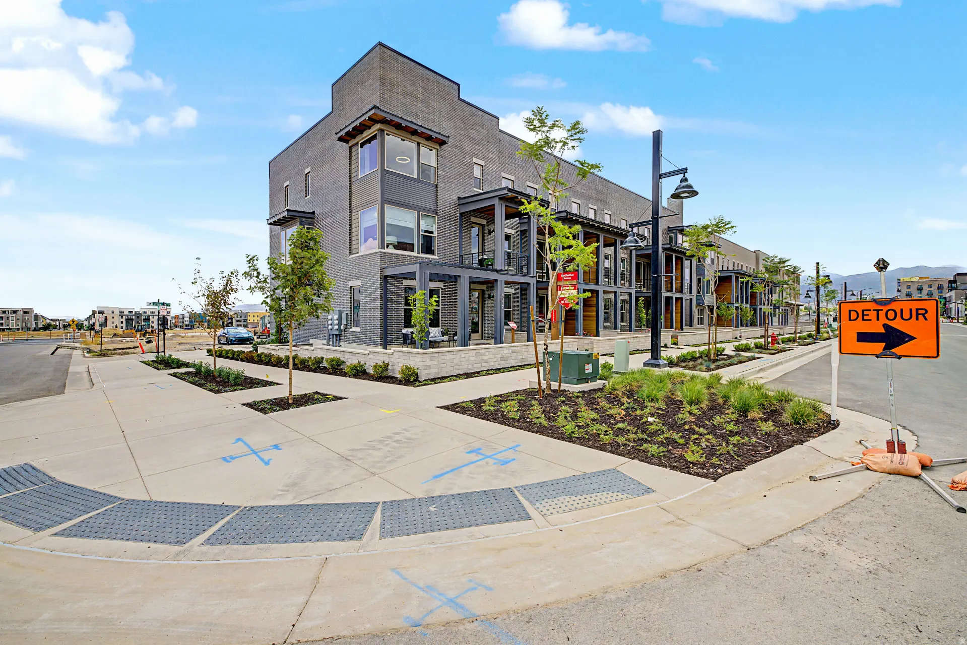 Contemporary multi-story townhome featuring a dark brick facade and multiple window styles
