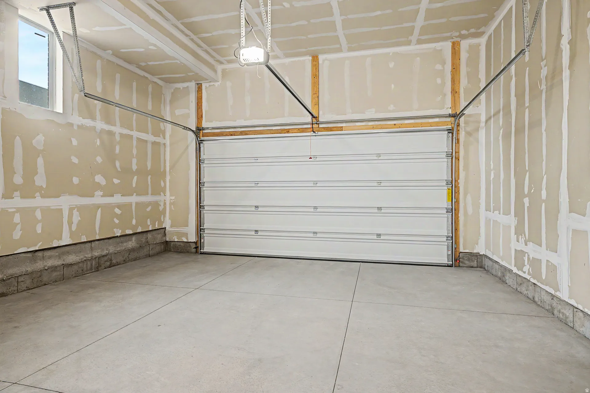 Spacious garage featuring a concrete floor, an overhead door with opener, and a single window