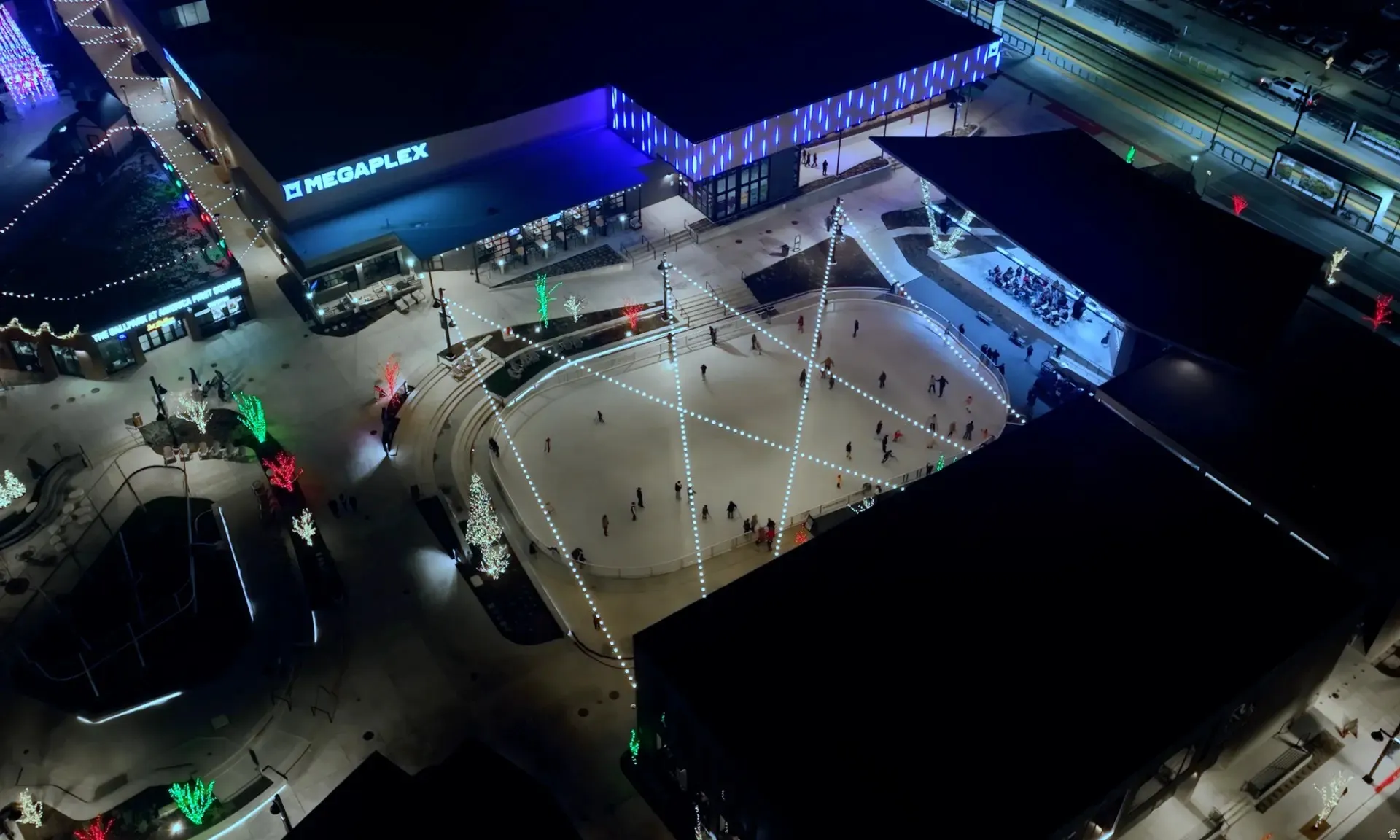Central plaza featuring an ice skating rink, string lighting, and commercial buildings