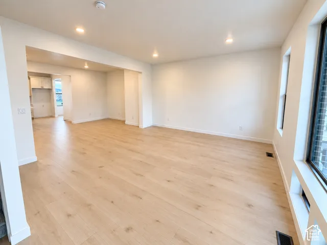 Expansive room featuring light wood-finish flooring, recessed lighting, and large windows