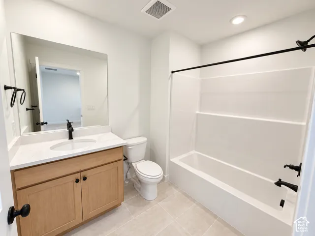 Bathroom featuring a light wood-finish vanity, white countertop, matte black fixtures, tub with shower, and tile flooring