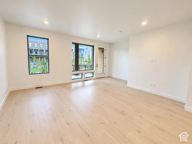 Light wood-finish flooring, recessed ceiling lighting, a single pane window, and a window with lower operable transoms