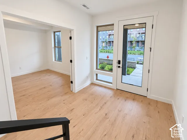 Light wood-finish flooring throughout, white painted walls, and a white framed glass panel door