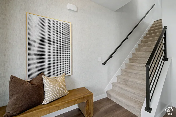 Carpeted staircase featuring black metal railings and a wall-mounted handrail