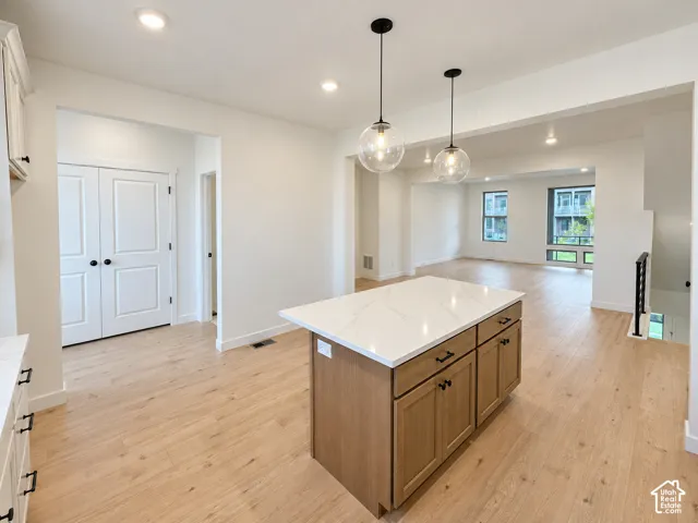 Central kitchen island featuring a light-toned wood finish and a white countertop