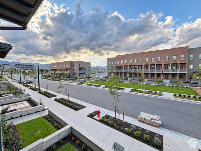 Modern townhome architecture featuring brick and paneling facade, multiple balconies, and integrated street-level landscaping