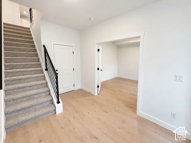 Hardwood-style flooring, white trim details, and a carpeted staircase with a modern black railing