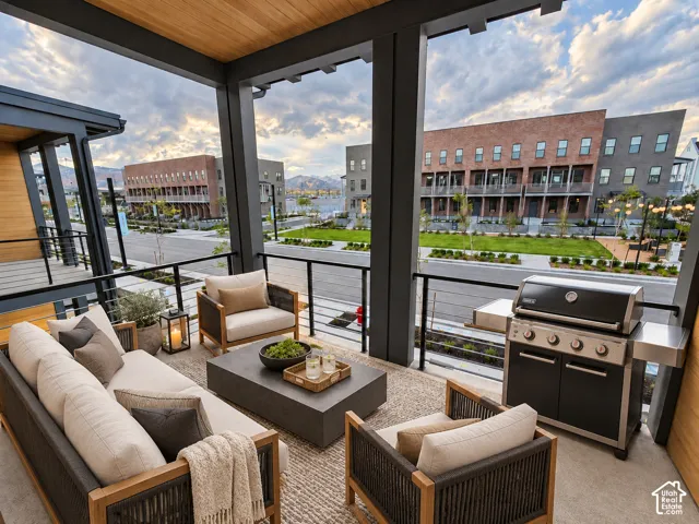 Covered outdoor patio with a wood-finish ceiling, dark-framed railings, and an outdoor grill