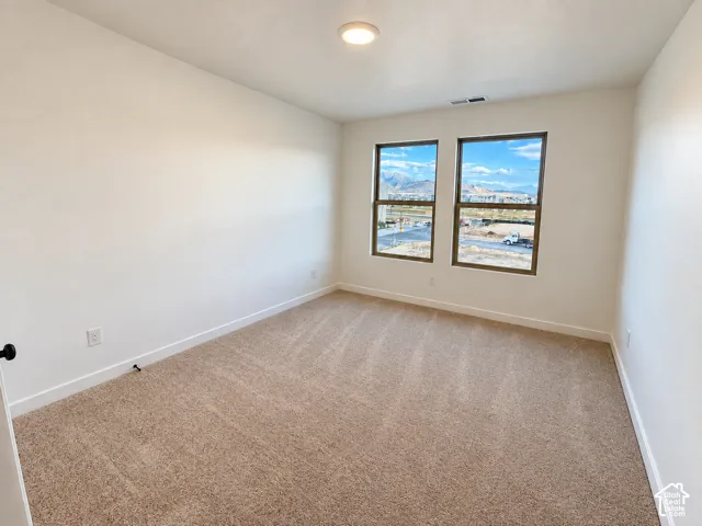 Recessed ceiling light, two windows with dark frames, light-colored walls, and neutral carpet flooring