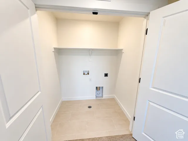 Laundry area featuring tile flooring, a built-in shelf, and utility connections