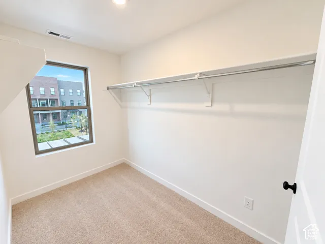 Neutral-toned wall-to-wall carpeting, white walls, and a single window with dark framing