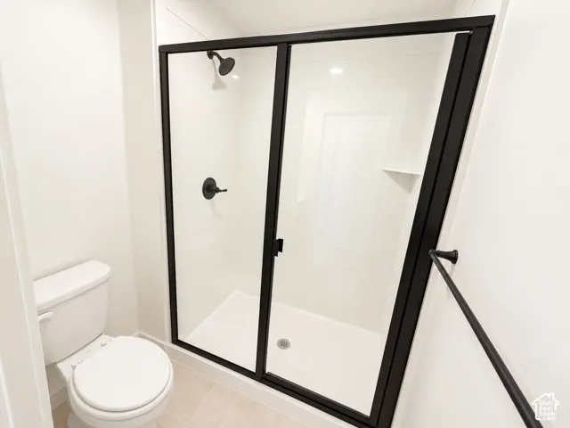 Shower enclosure with matte black framing, sleek shower fixtures, and integrated shelving